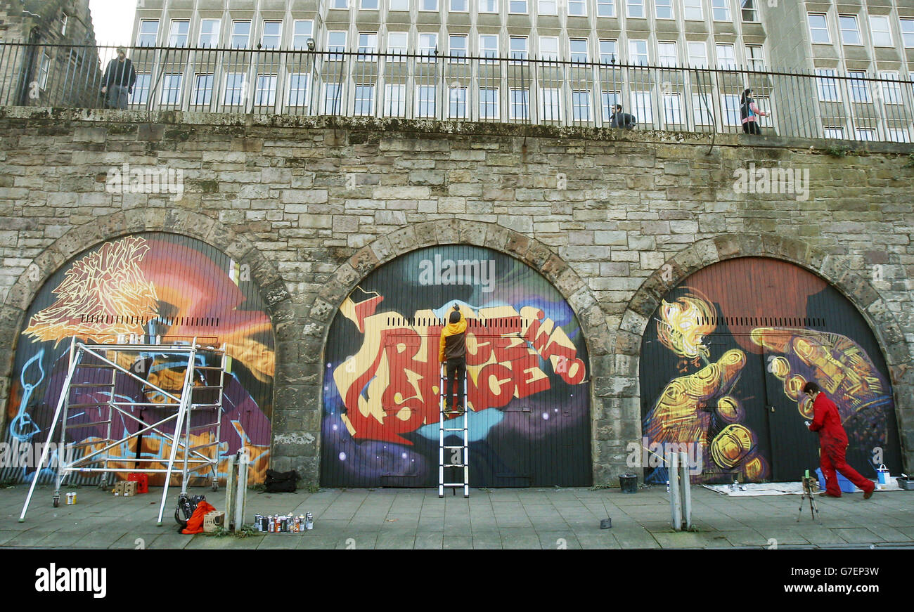 Los artistas de graffiti ponen los toques finales a sus piezas en el proyecto de arte callejero más grande de Escocia, en el corazón del casco antiguo de Edimburgo, donde una serie de lienzos en constante cambio durarán casi medio kilómetro. Foto de stock