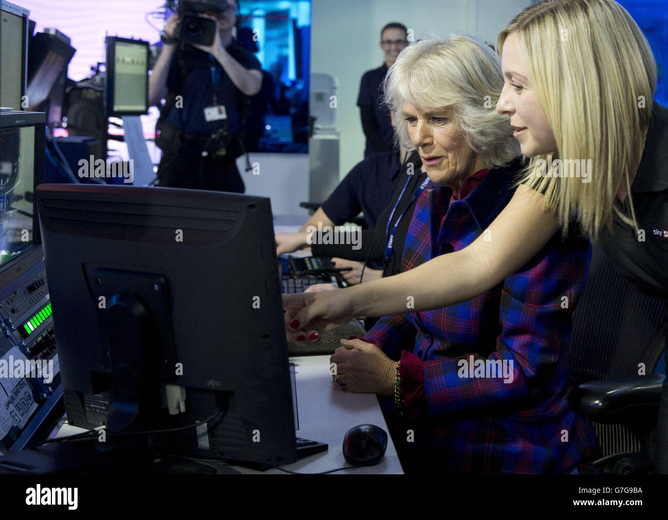 La duquesa de Cornwall mira un monitor con la empleada de Sky Rachel Applin, que controla remotamente las cámaras de televisión en el estudio de noticias Sky Sports en Londres durante una visita a Sky con el Príncipe de Gales. Foto de stock