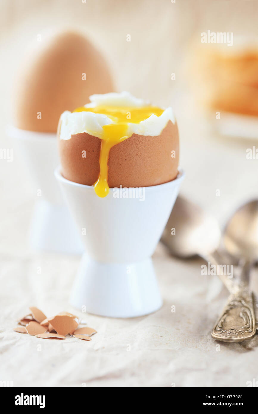 Huevo suave en la base con la yema actual contra otros huevos para desayunar Foto de stock