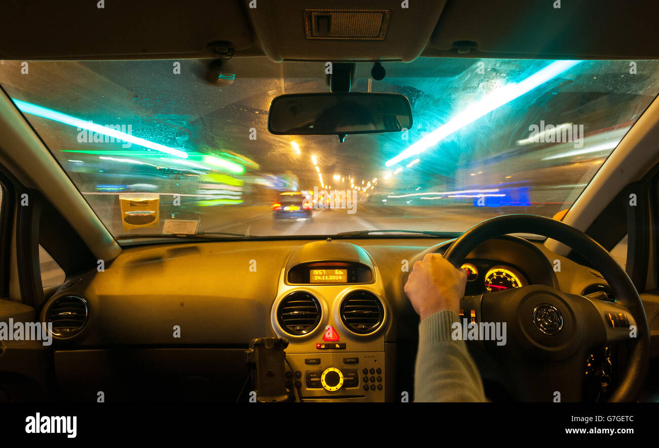 Foto genérica de un hombre conduciendo un coche en el tráfico por la noche. Foto de stock