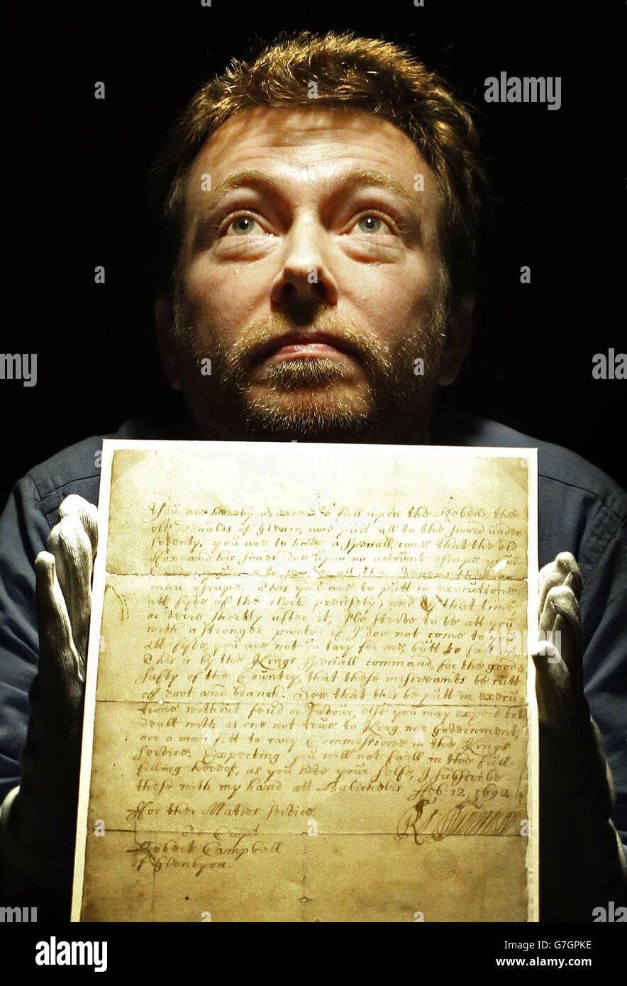 El curador de libros raros Robert Betteridge con un documento que ordenó la masacre de Glencoe, parte de la exposición Juego de las Coronas en la Biblioteca Nacional de Escocia en Edimburgo. Foto de stock