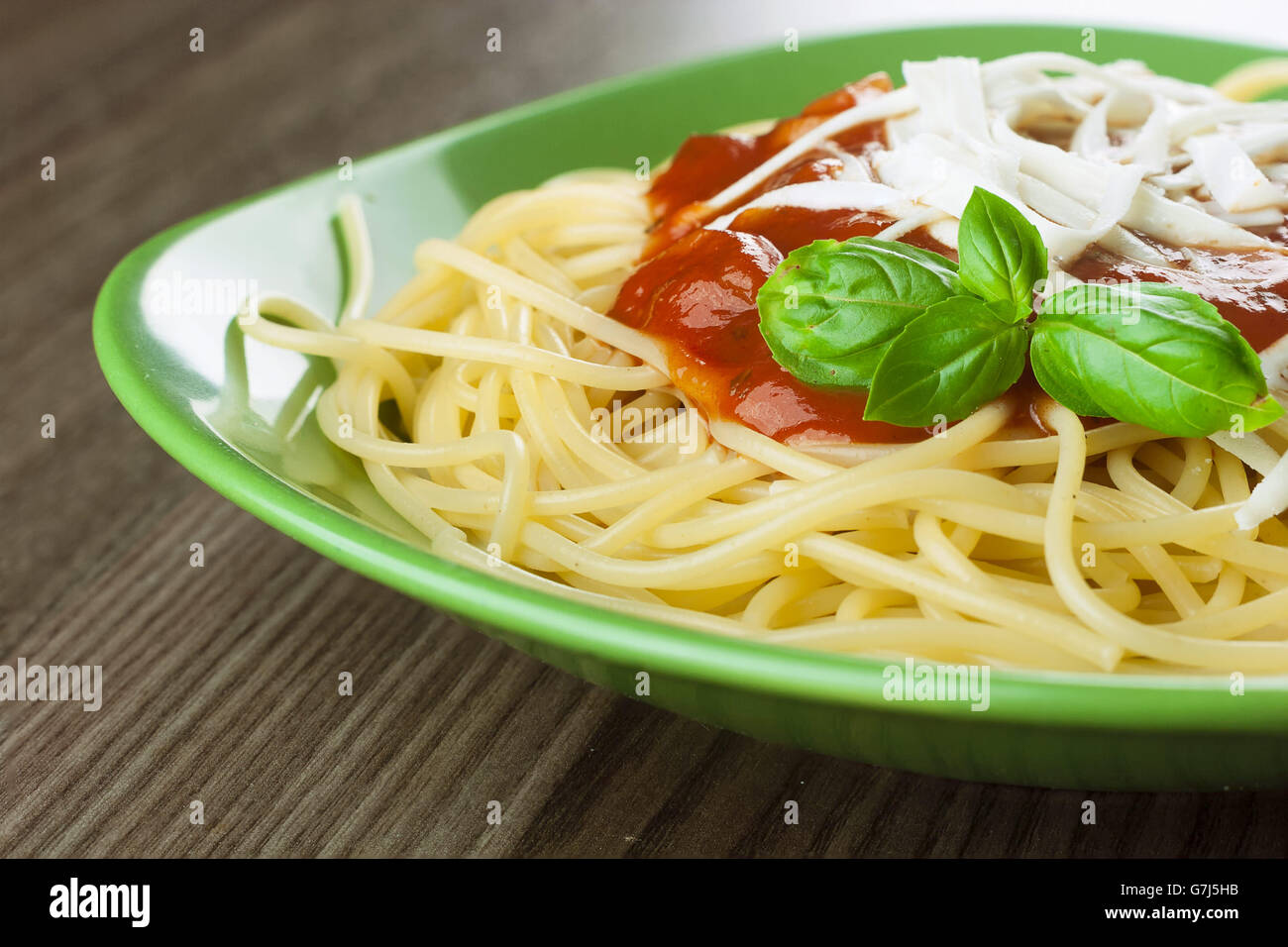 Cocinó espaguetis con tomate italiano tradicional souse servido en una placa verde sobre una mesa de madera Foto de stock