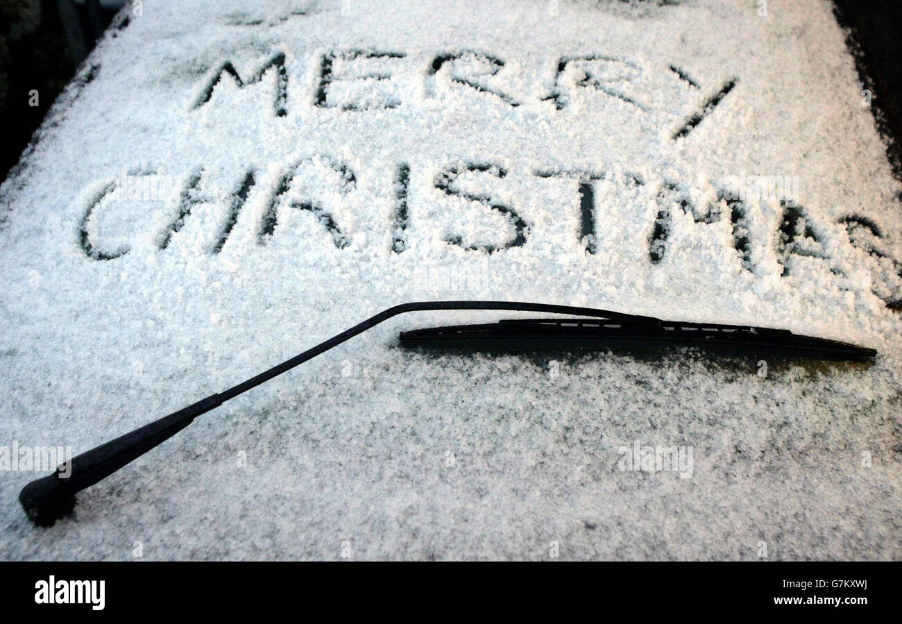 Un mensaje de navidad escrito en la nieve en el parabrisas de un coche. Foto de stock