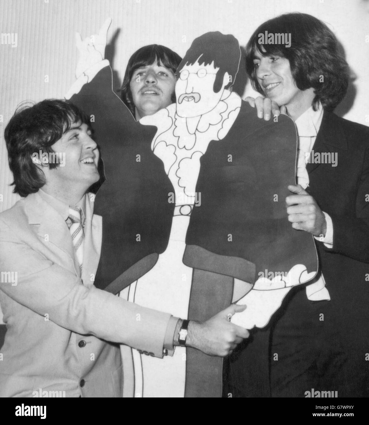 Una caricatura a tamaño real cortada de Beatle John Lennon gana la atención amorosa de sus tres compañeros en vivo, (de izquierda a derecha) Paul McCartney, Ringo Starr y GEORGE HARRISON en una película de dibujos animados de prensa previa de 'The Yellow Submarine' en Bowater House, Knightsbridge, Londres. Foto de stock