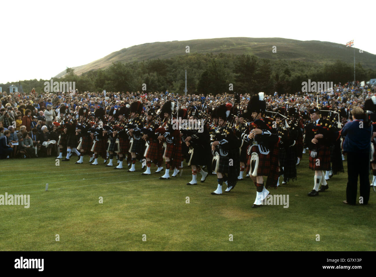 Bandas masacradas se llevan a la arena durante el Encuentro de la Sociedad Braemar Royal Highland en 1981. Foto de stock