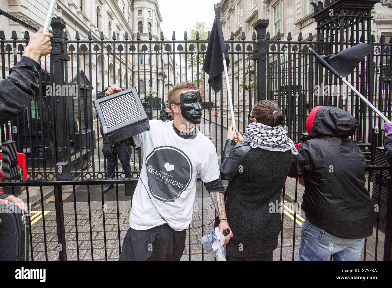 Un puñado de manifestantes con máscaras y banderas negras agitadas se encuentran junto a las puertas de la entrada de Downing Street gritando cantos anticonservadores y afirmando que el primer ministro David Cameron está lleno de mentiras. Foto de stock