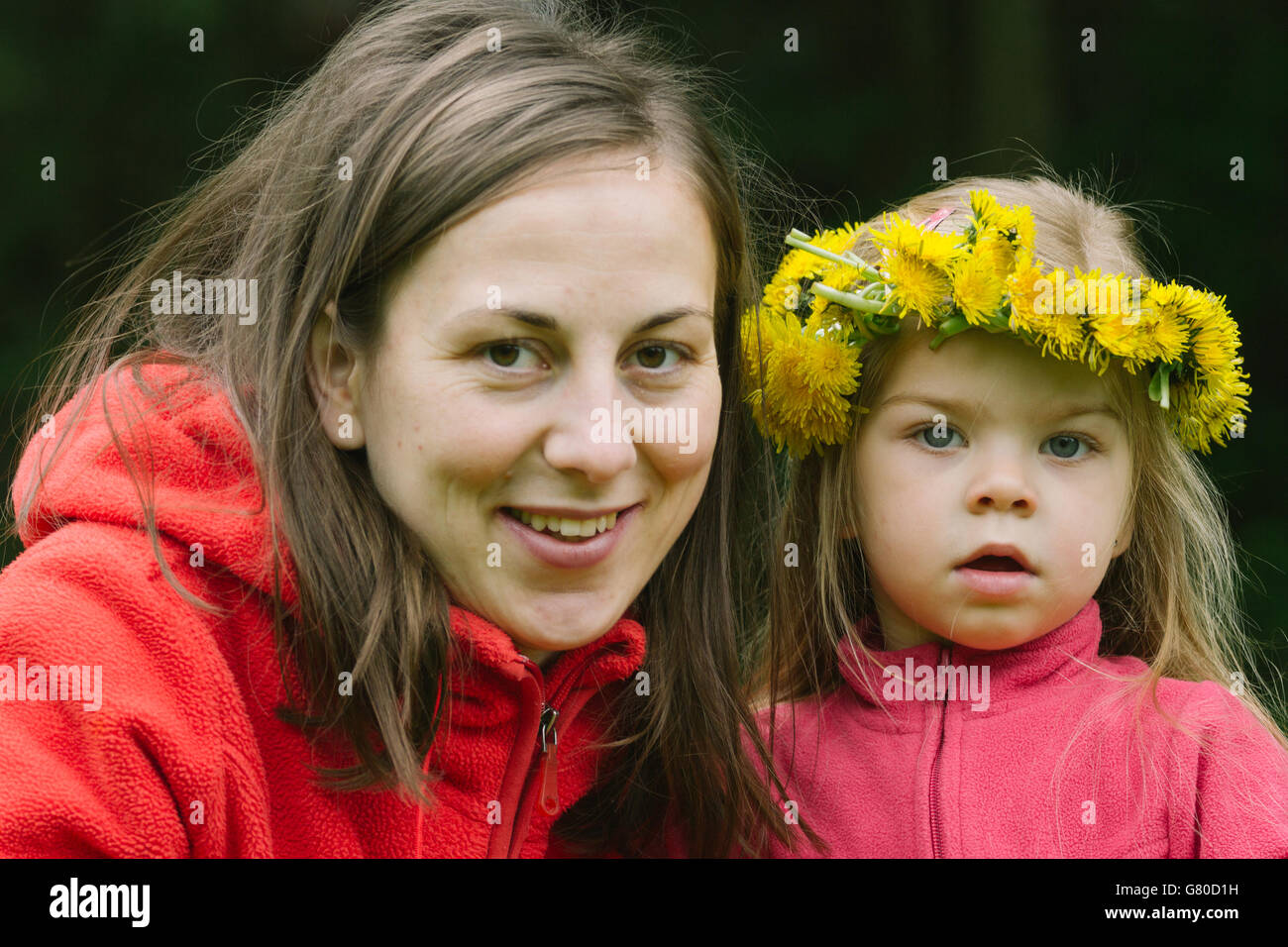 Photographu cerca de una joven madre y su hija en medio de la naturaleza, portando guirnalda de flores Foto de stock