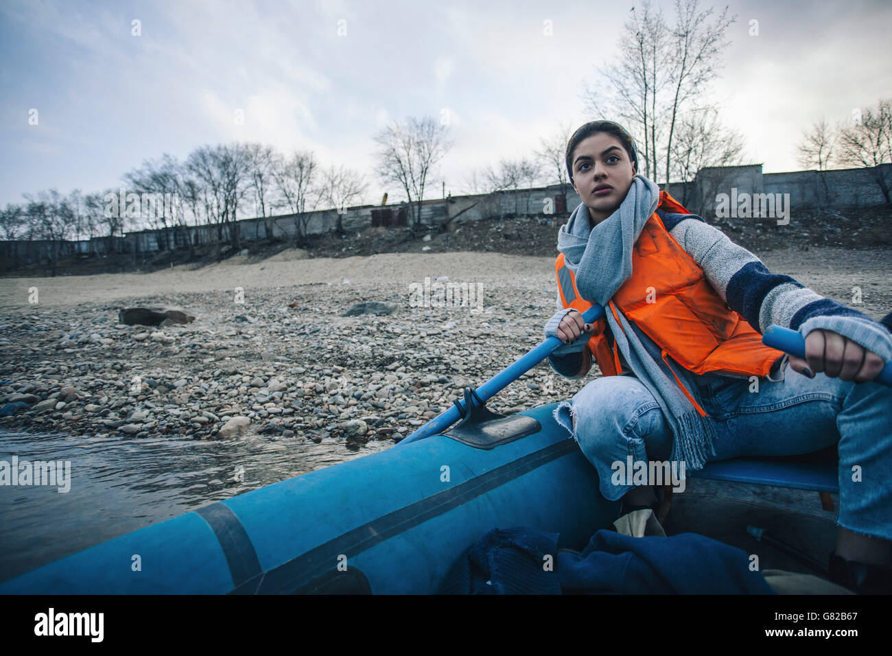 Adolescente vistiendo chalecos salvavidas mientras canotaje en el lago Foto de stock