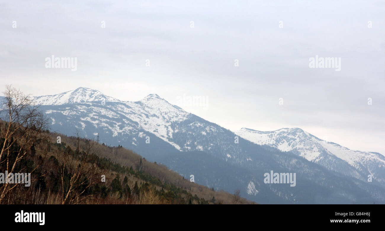 Las crestas de las montañas cubiertas de nieve y cielo nublado. Foto de stock