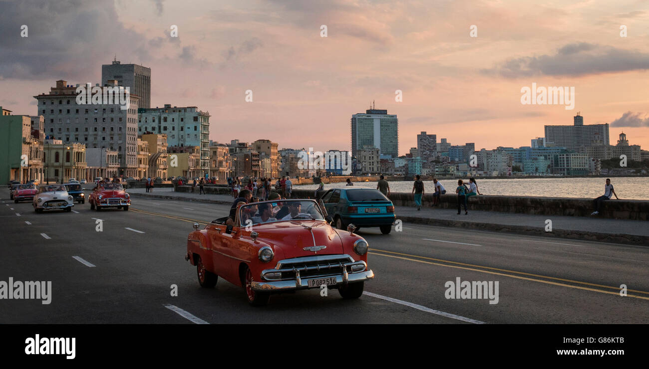 Coches clásicos conduciendo a lo largo del Malecón (carretera de la costa) en La Habana, Cuba Foto de stock
