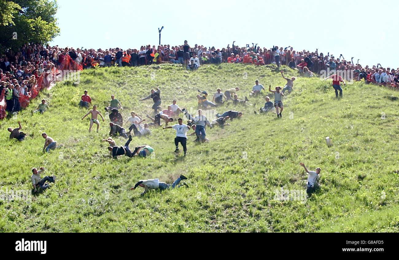 Los competidores persiguen un doble queso Gloucester por una pendiente empinada, para el antiguo deporte del diablo. Más de 4,000 espectadores acude al extraño evento que se ha celebrado durante siglos y se cree que tiene sus raíces en un festival de paganos para celebrar el regreso de la primavera. Foto de stock