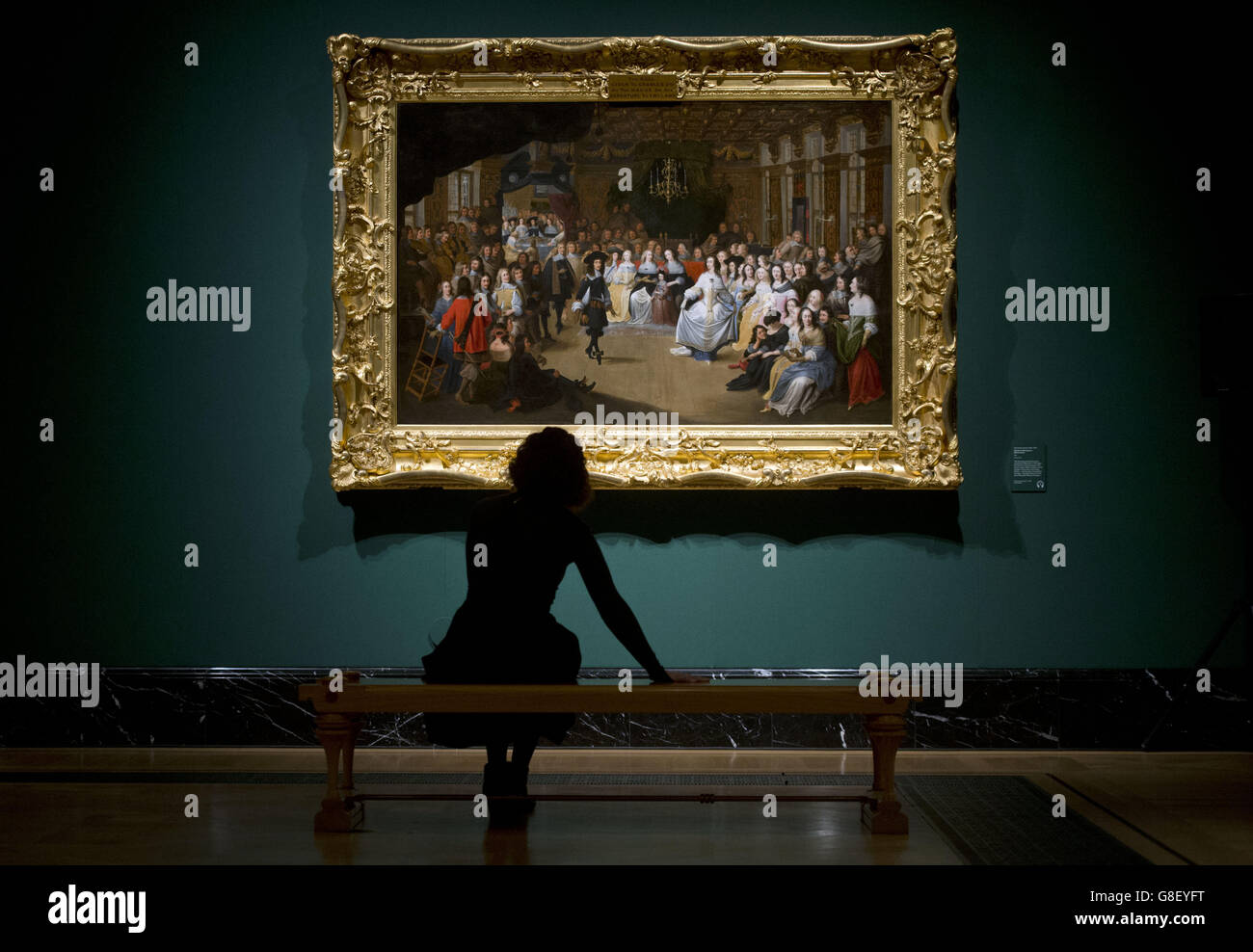 Un empleado del Royal Collection Trust ve la obra de arte "Charles II danzando en una pelota en la corte" de Hieronymus Janessens (1660) en la Queen's Gallery en el Palacio de Buckingham, Londres. Foto de stock