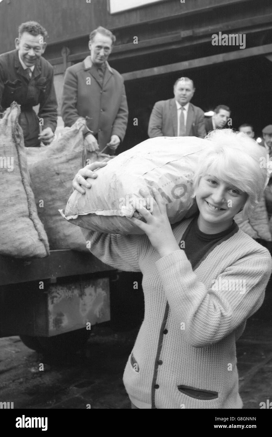 Sandra Sherlock, de 17 años, de Elsworth Street, Leeds, hace un trabajo ligero de una bolsa de combustible que abultaba durante su trabajo como "hombre de carbón" en el negocio de su familia. Ella dijo: "Lo he estado haciendo desde que salí de la escuela. Mi madre conduce el camión y yo ayudo a entregar el carbón, el coque y los ladrillos de carbón. Me gusta la vida, y llevar sacos de carbón no significa nada para mí. A menudo estoy arriba y apagado en las rondas a las cinco de la mañana. Foto de stock