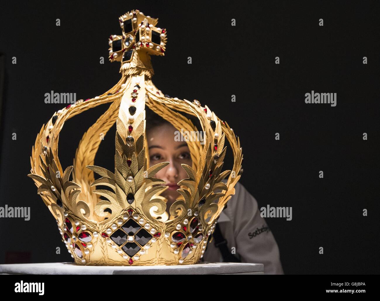Un técnico de galería examina una corona hecha de 3,000 hojas de oro cortadas y anotadas individualmente por el artista Zoe Bradley, que se exhibirá durante la próxima venta de Sotheby's Royal and Noble Descent' que tendrá lugar entre el 14 y el 18 de enero en Londres. Foto de stock
