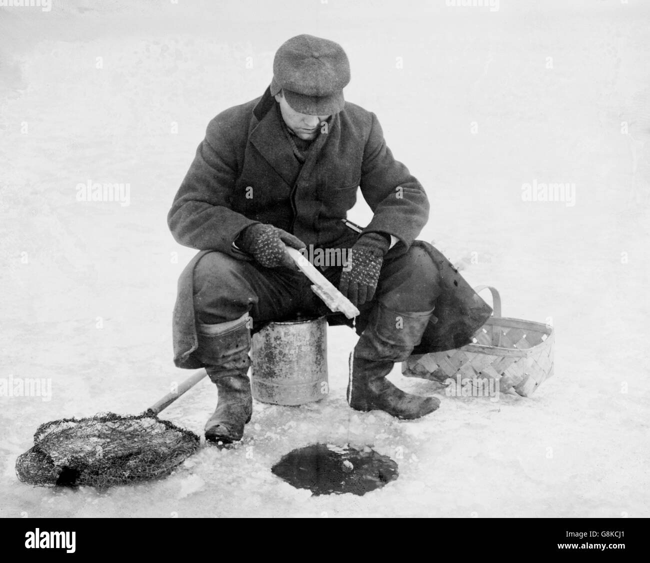 Hombre que pesca a través del agujero en el hielo, el Servicio de Noticias Bain, circa 1910 Foto de stock