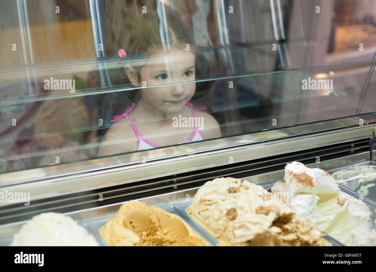 Niña quiere helado en la pastelería. Reflexiones sobre helados gafas de contador Foto de stock