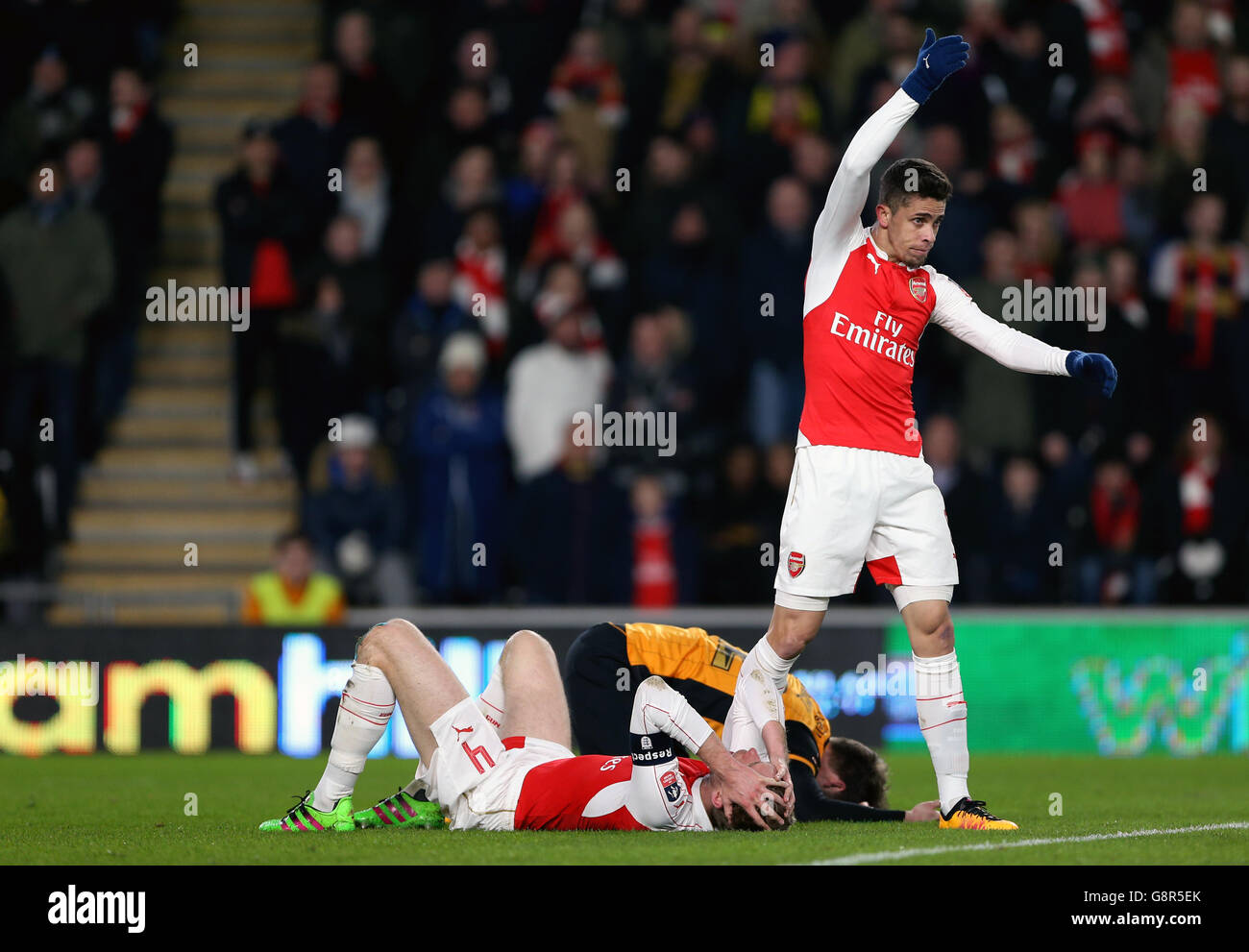 Gabriel Paulista del Arsenal reacciona como el per Mertesacker del Arsenal (piso) colisiona Con Nick Powell de Hull City Foto de stock
