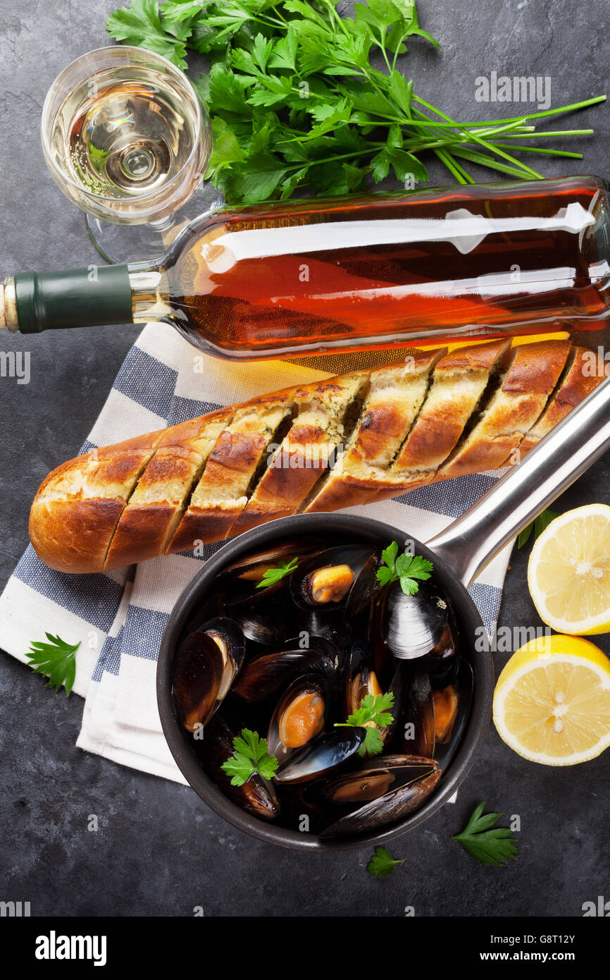 Mejillones en olla de cobre y vino blanco sobre la mesa de piedra. Vista superior Foto de stock