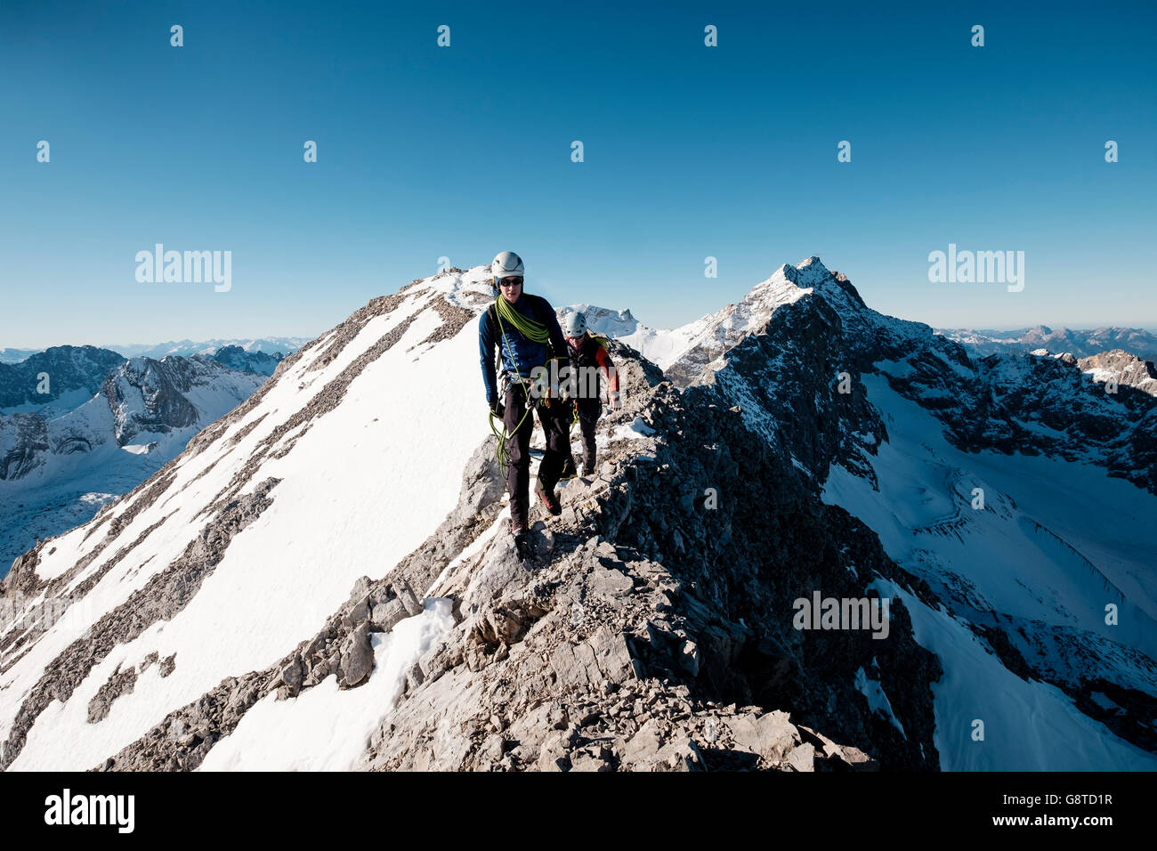 Dos montañeros trekking sobre el pico de la montaña en los Alpes Foto de stock