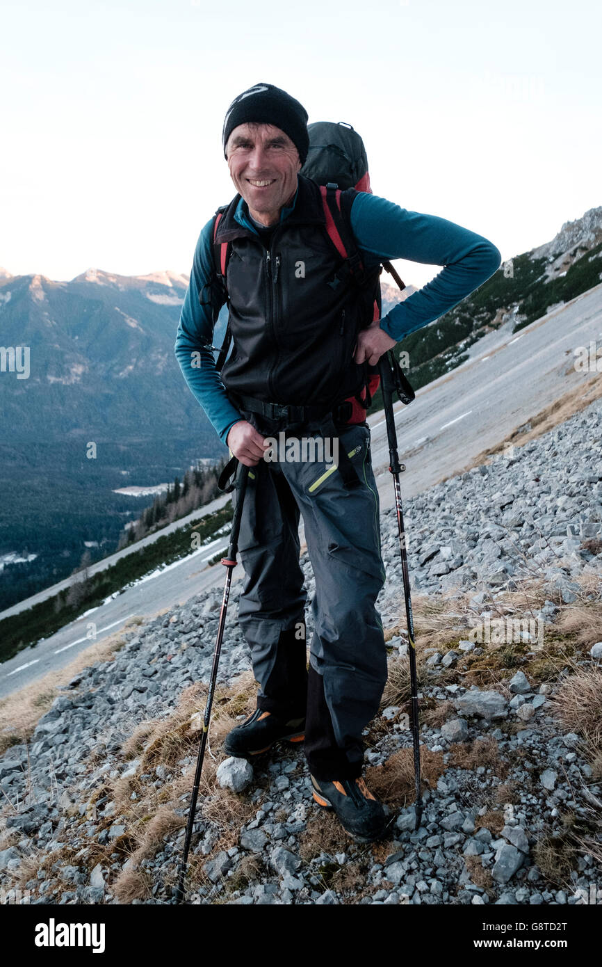 Guía de montaña con mochila y bastones de senderismo en los Alpes Foto de stock