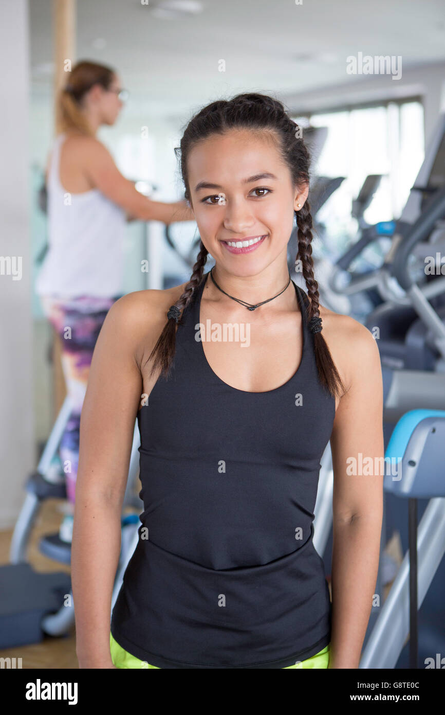 Mujer en el club de salud con equipo de ejercicio en segundo plano. Foto de stock