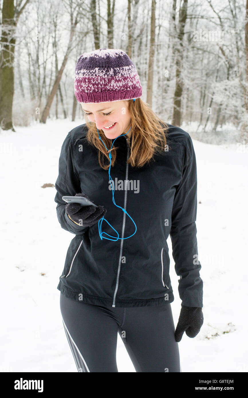 Mitad mujer adulta con knit hat utilizando smart phone en invierno Foto de stock
