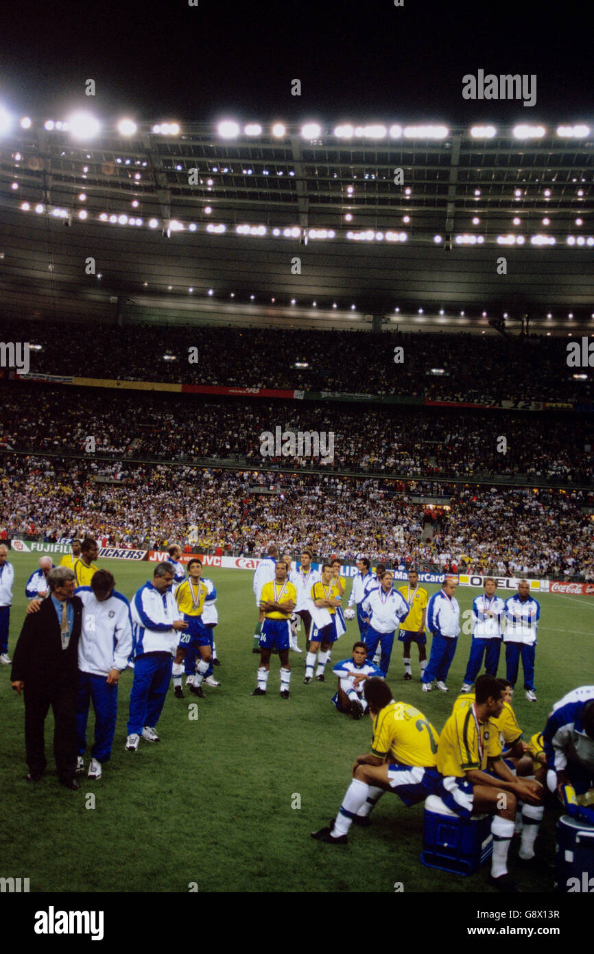Los jugadores y funcionarios de Brasil desalentados miran desde el centro Del campo como Francia recoger la Copa del Mundo Foto de stock