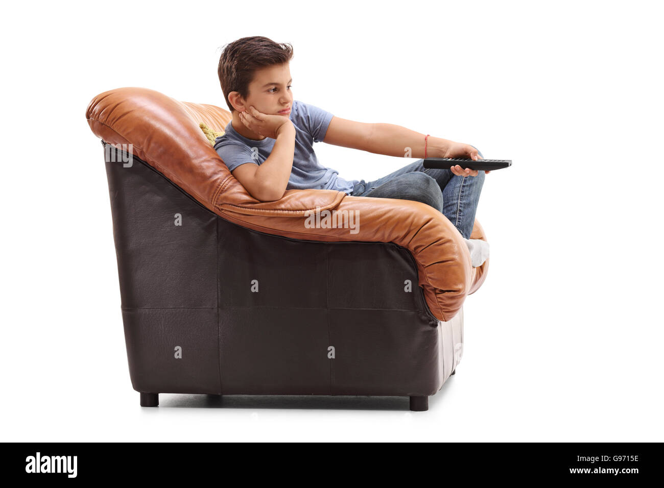 Aburrido chico cambiar canales en televisión sentado en un sillón aislado sobre fondo blanco. Foto de stock