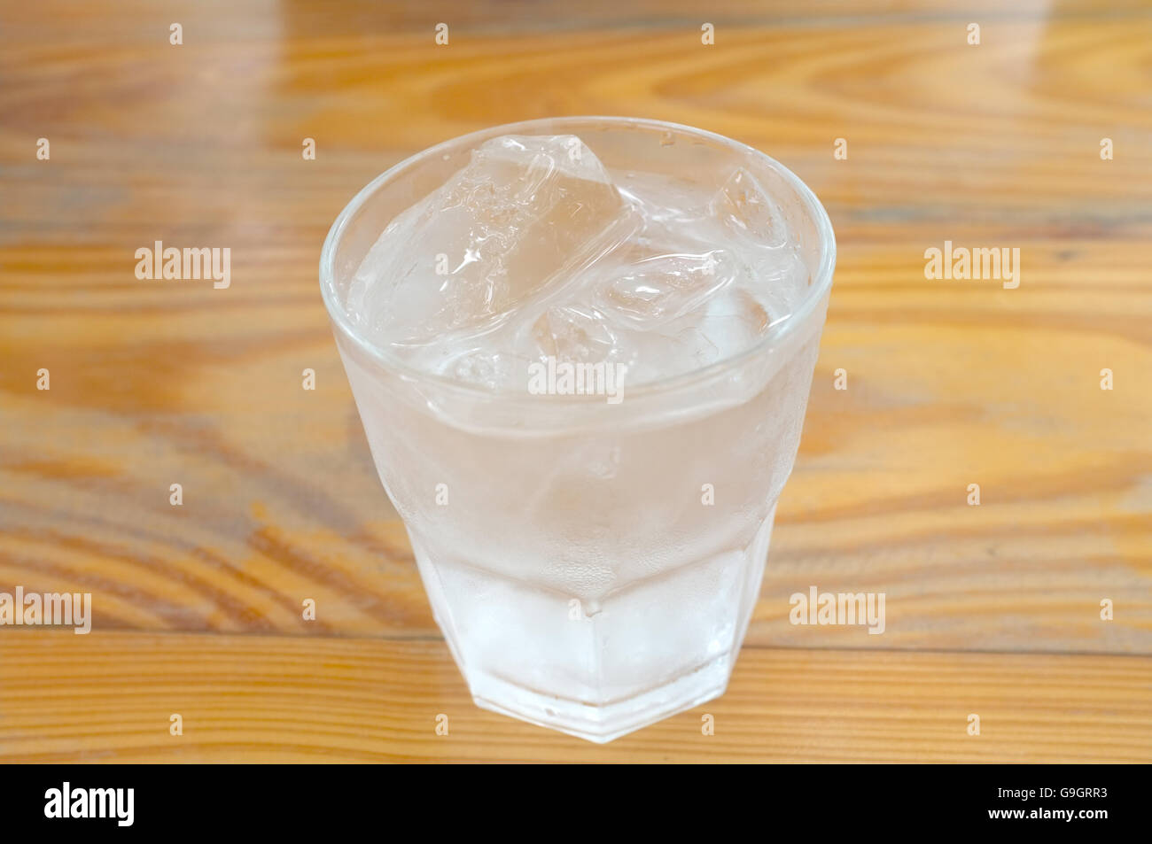 Vaso de agua pura y cubo de hielo sobre fondo de madera Foto de stock