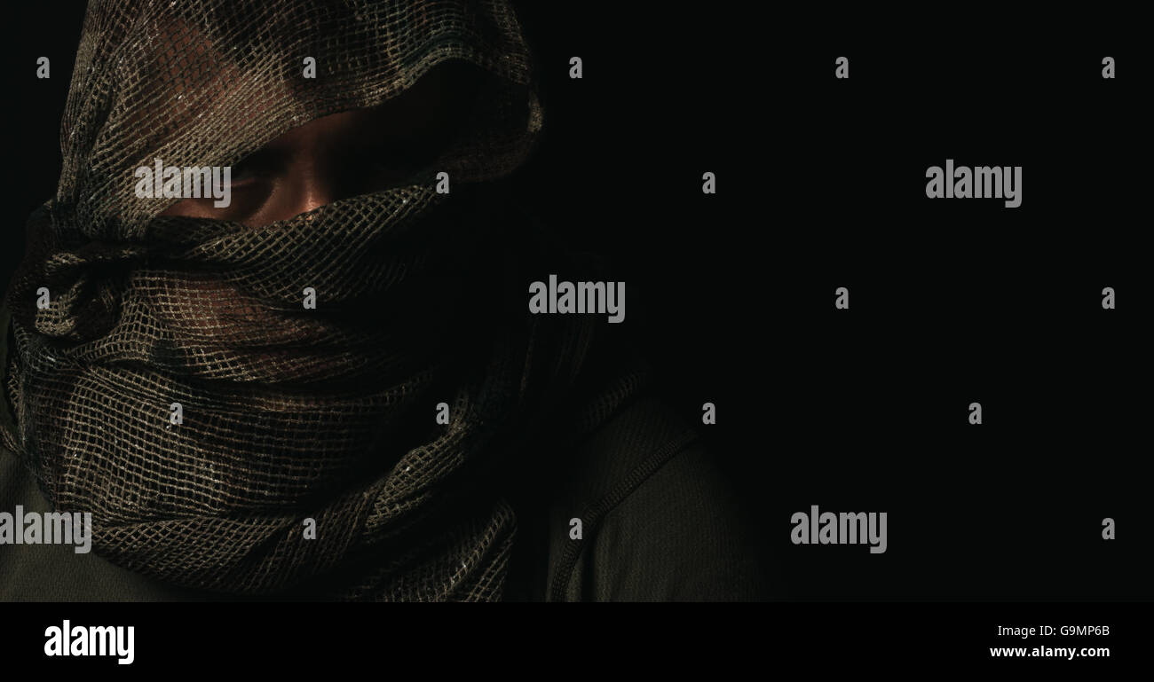 Ocultar sniper con bufanda de camuflaje por encima de la cabeza en la parte delantera del fondo negro aislado Foto de stock