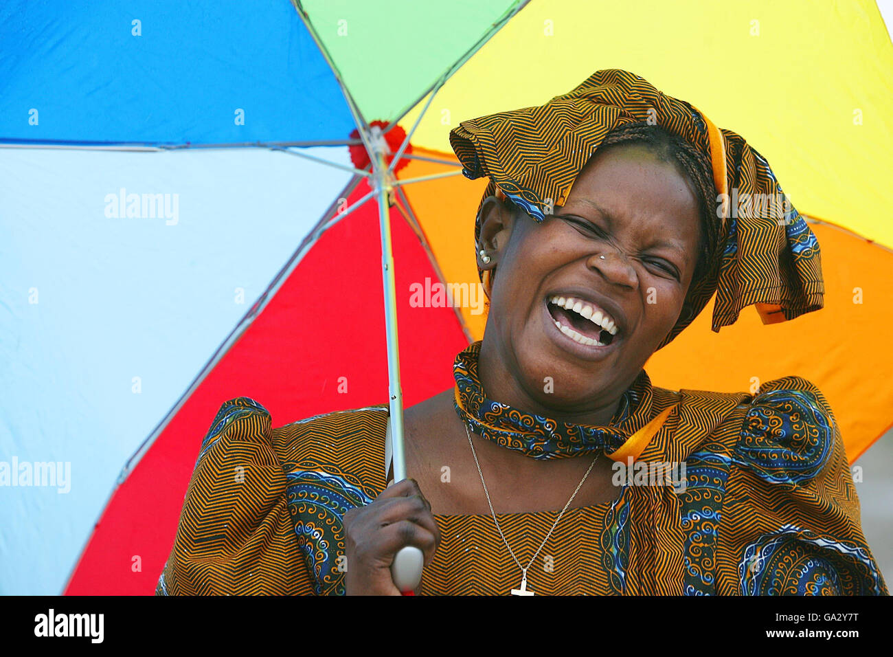 Mónica Gumba, de Kenia, intenta mantenerse seca mientras se lanza la línea del Festival Anual de las culturas del Mundo en Dun Laoghaire, Dublín. Foto de stock