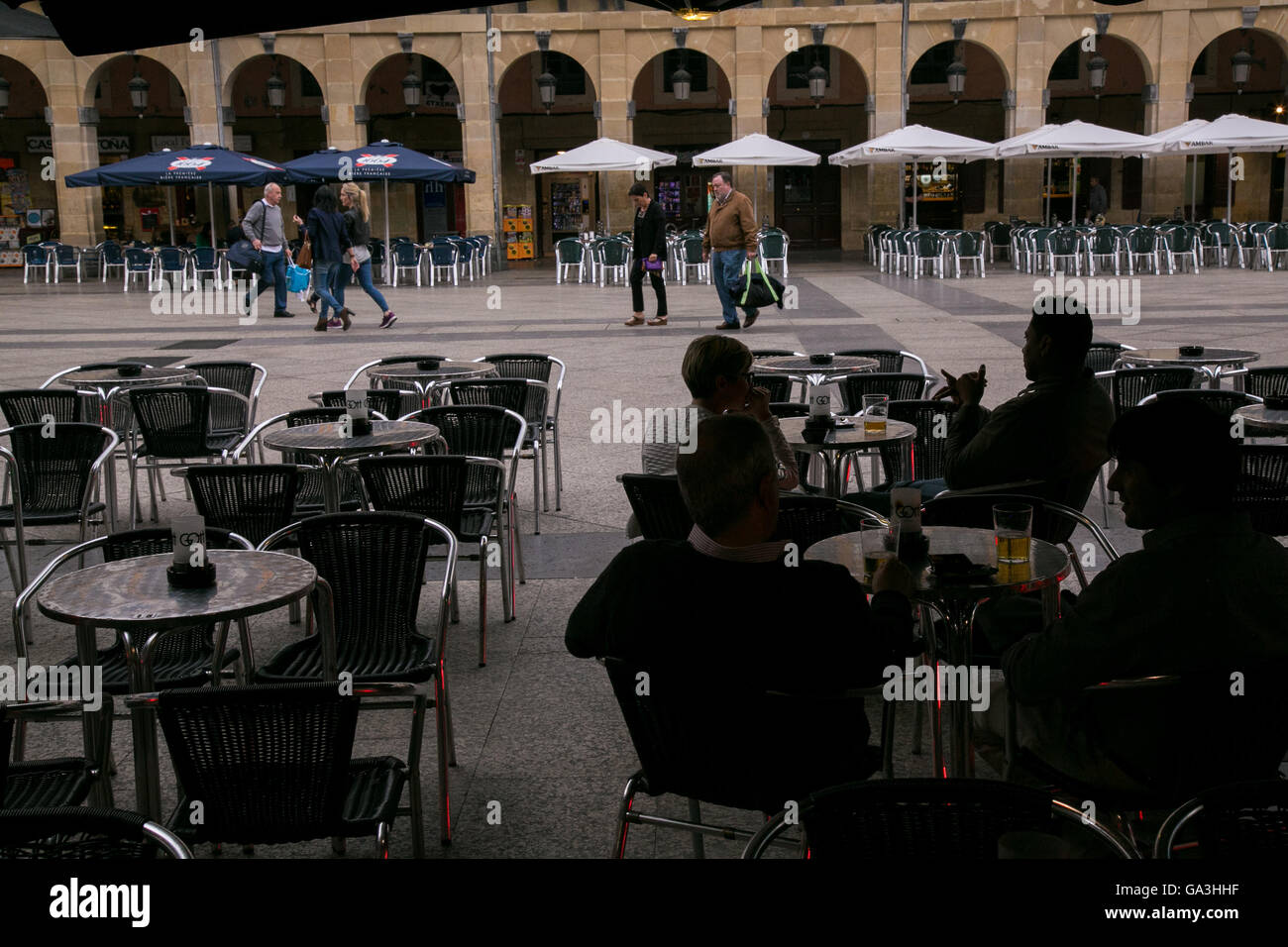 Personas sentadas en una plaza pública en San Sebastián, España. Foto de stock