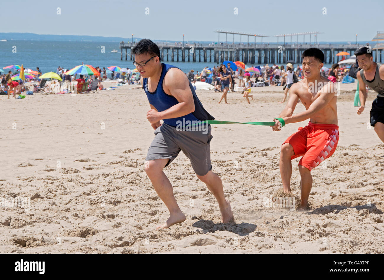 Joven asiática trabajando en la playa en Coney Island girando hacia adelante contra la resistencia. Foto de stock