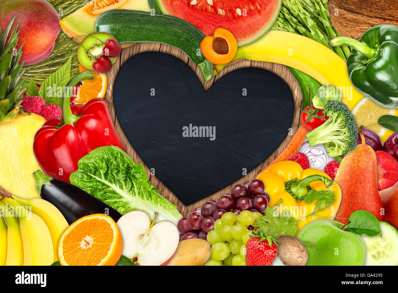 Bastidor en forma de corazón de frutas y verduras en el fondo de la pizarra Foto de stock
