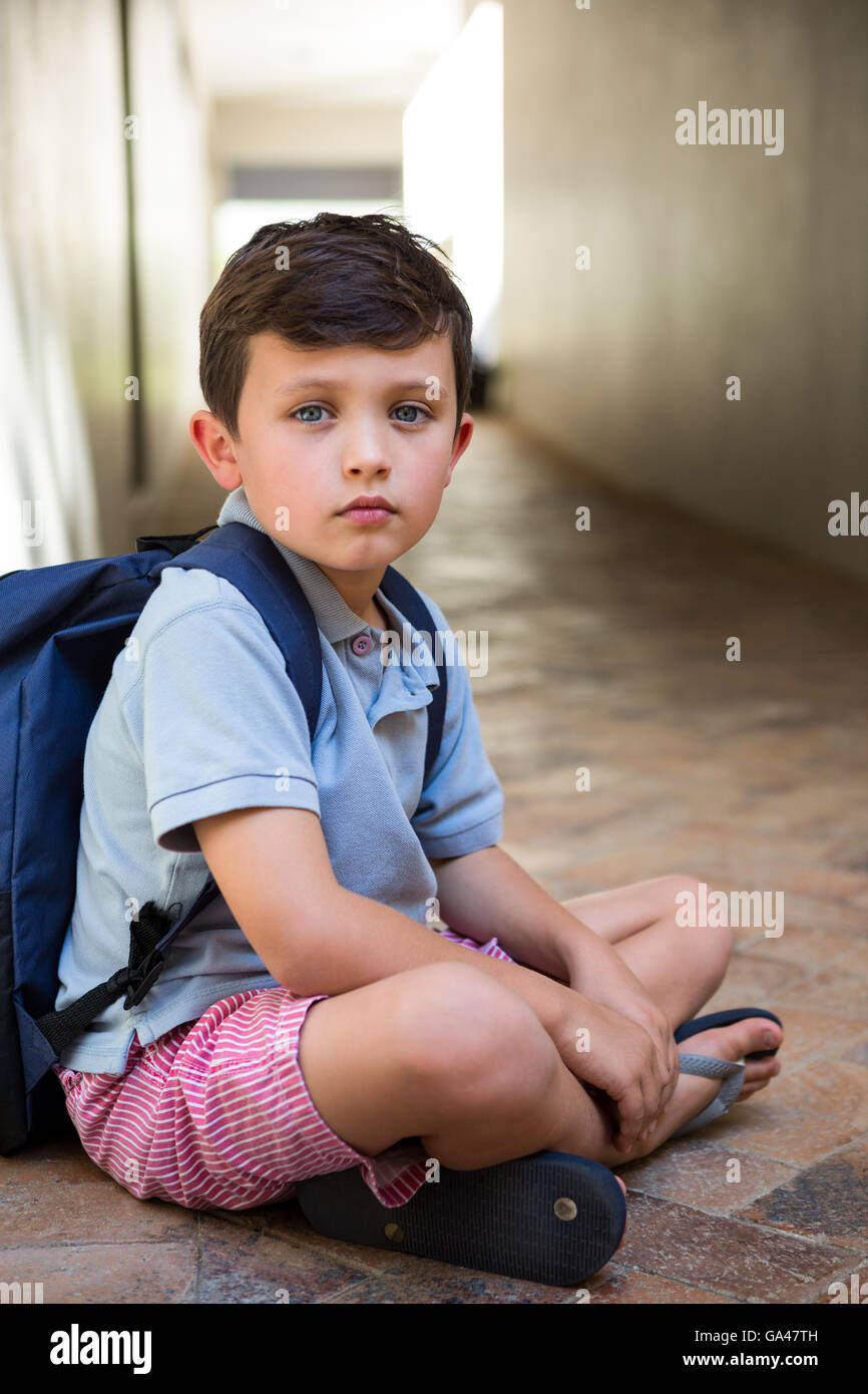 Muchacho sentado en el pasillo de la escuela Foto de stock