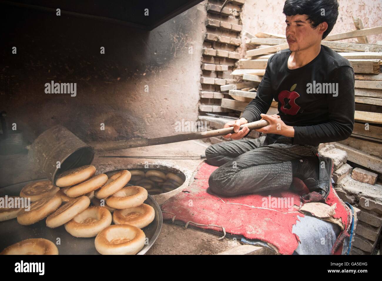 Kashgar, China, Región Autónoma de Xinjiang Uygur. El 28 de junio, 2016. Un hombre se coció Nang, una especie de panqueque crujiente, alimento básico de la población de Kashgar, de un horno de ladrillo calentado en Kashgar, en el noroeste de China la Región Autónoma de Xinjiang Uygur, 28 de junio de 2016. Panaderos pasó más de 16 horas haciendo unas cuatro o cinco mil nangs para satisfacer las necesidades como romper el ayuno se está acercando. © Bu Duomen/Xinhua/Alamy Live News Foto de stock