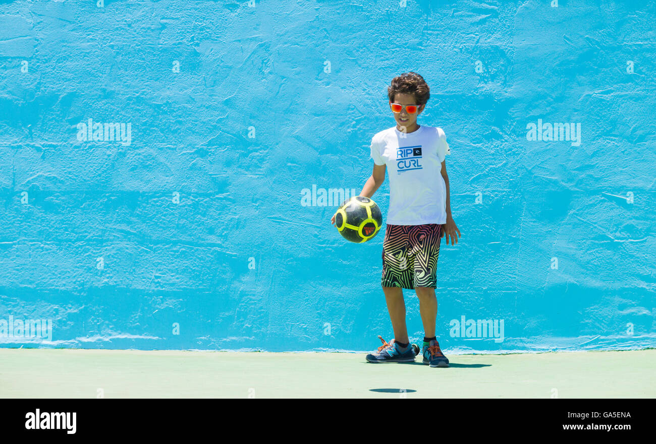 Pozo, Gran Canaria, Islas Canarias, España, el 03 de julio de 2016. Clima: Un niño juega fútbol contra una pared azul en la playa de sol glorioso en la primera ola la Copa del Mundo de 2016 eventos de windsurf en Pozo en la costa oriental de la isla de Gran Canaria. Pozo es famoso (y temido por algunos) por su "nuclear" vientos estivales, que puede superar los 50 nudos. La competencia tiene lugar entre el 3 al 10 de julio. Crédito: Alan Dawson News/Alamy Live News Foto de stock
