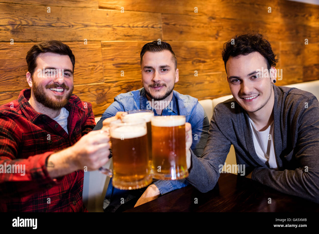 Amigos varones tostado de cerveza en restaurante Foto de stock