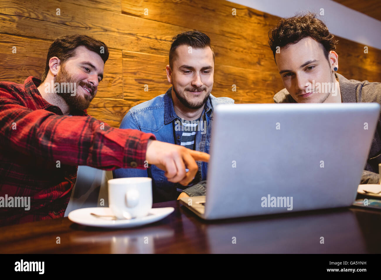Amigos varones usando el portátil en el restaurante Foto de stock