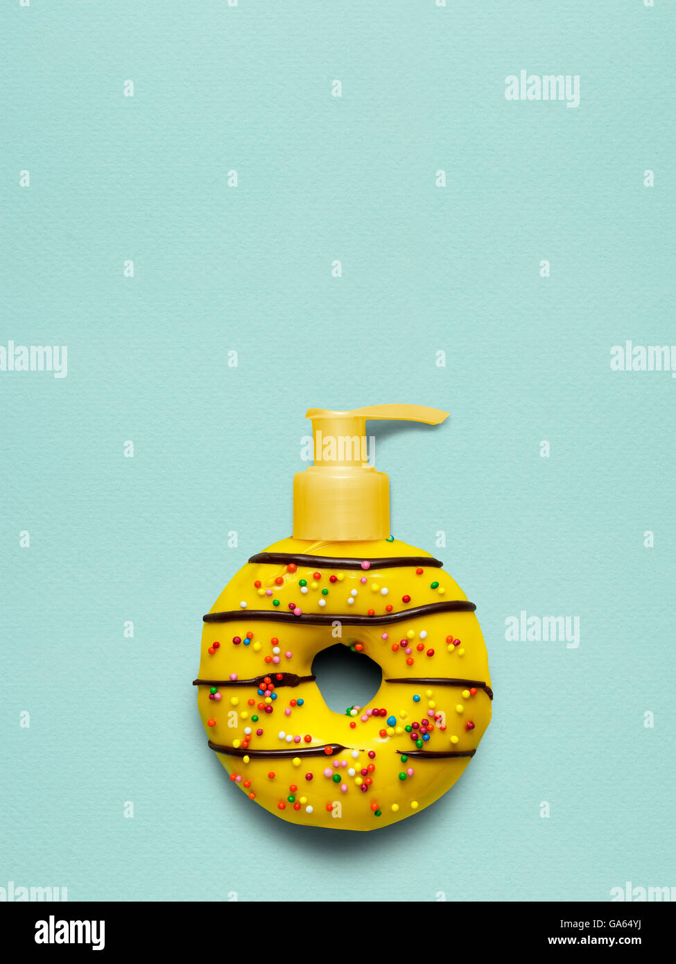 Todavía la vida creativa de un sabroso dulce donut amarillo con una bomba dispensadora descriptiva sobre fondo azul. Foto de stock