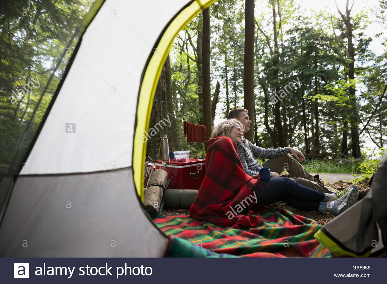 Par relajándose fuera de camping carpa en woods Foto de stock