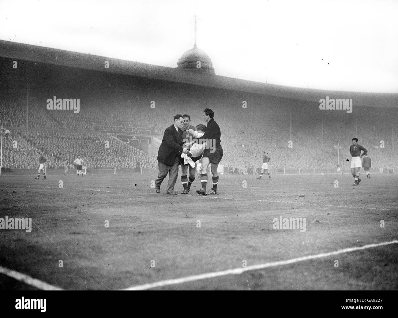 Stanley Mortensen (Inglaterra) es llevado fuera del campo por Gyula Grosics y Gyula Lorant después de haber sido herido durante el partido. El entrenador de Inglaterra Jimmy Trotter está a la izquierda. Foto de stock
