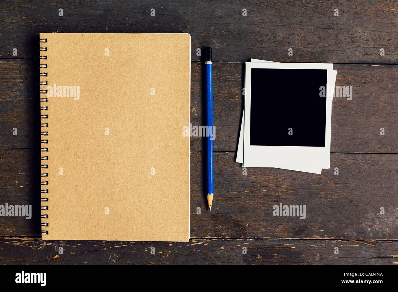 Libro y lápiz marrón con marco de foto en tabla de madera con el espacio de fondo Foto de stock