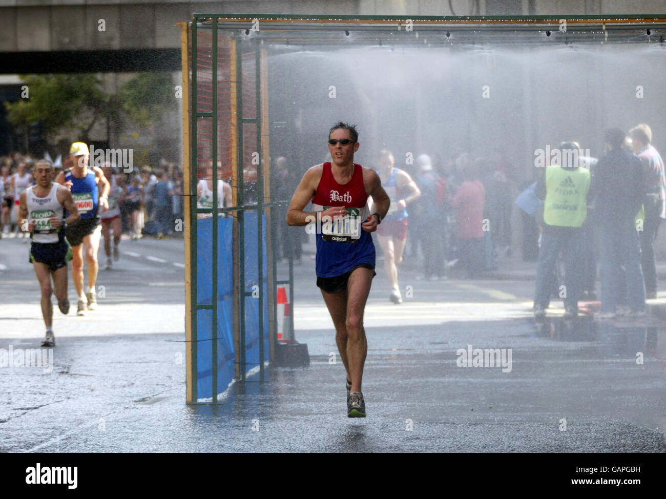Una ducha es opcional para los competidores a medida que corren La Ciudad en el Maratón de Londres Foto de stock