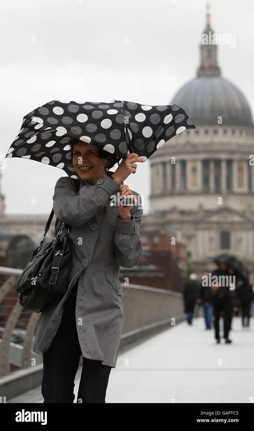 La gente lucha a través de los vientos fuertes y la lluvia mientras cruzan el Puente del Milenio, Londres. Foto de stock
