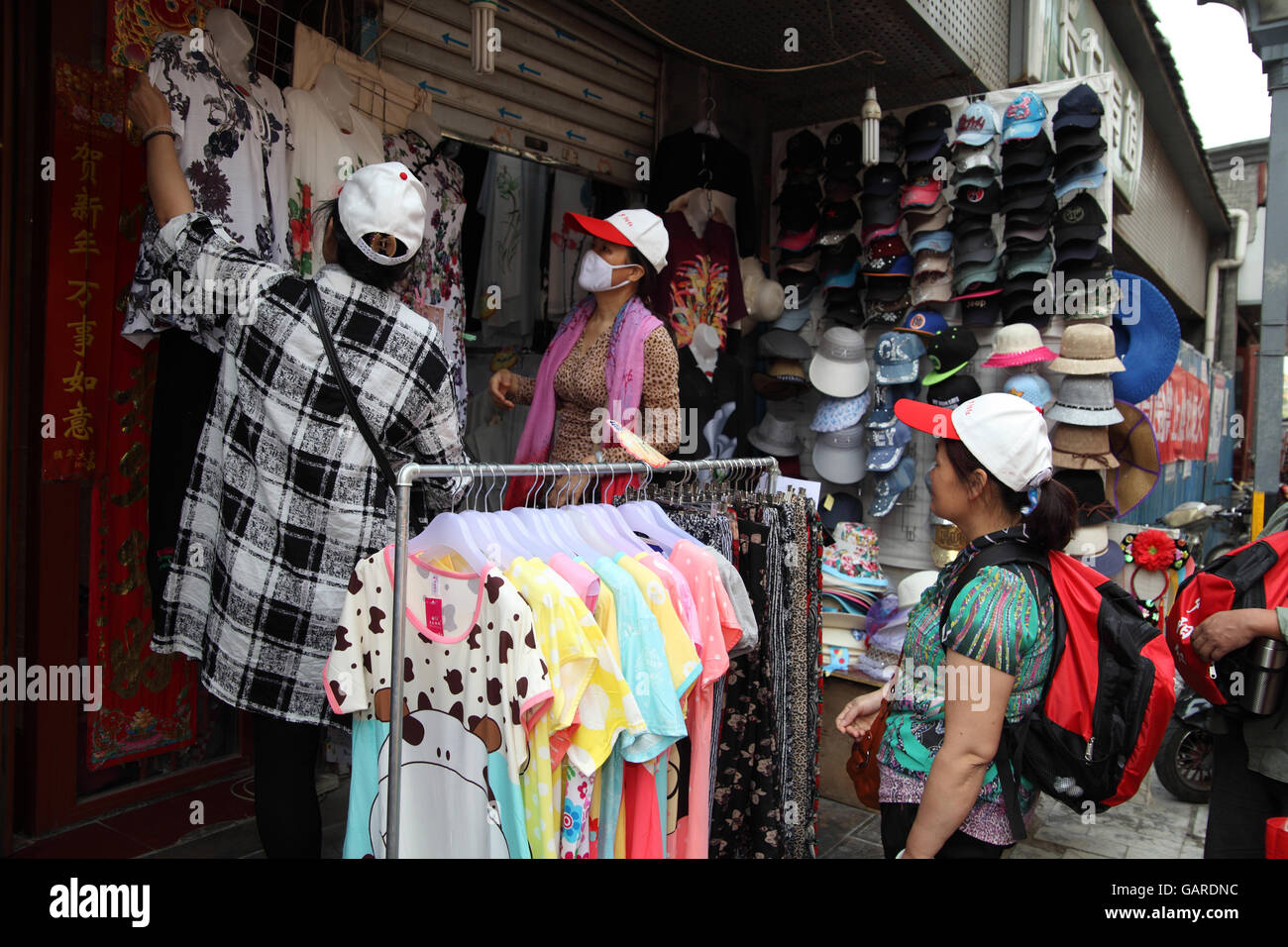 El hombre y la mujer china, uno que cubre su rostro contra la contaminación  mire ropa barata pueden comprar en un mercado al aire libre Fotografía de  stock - Alamy