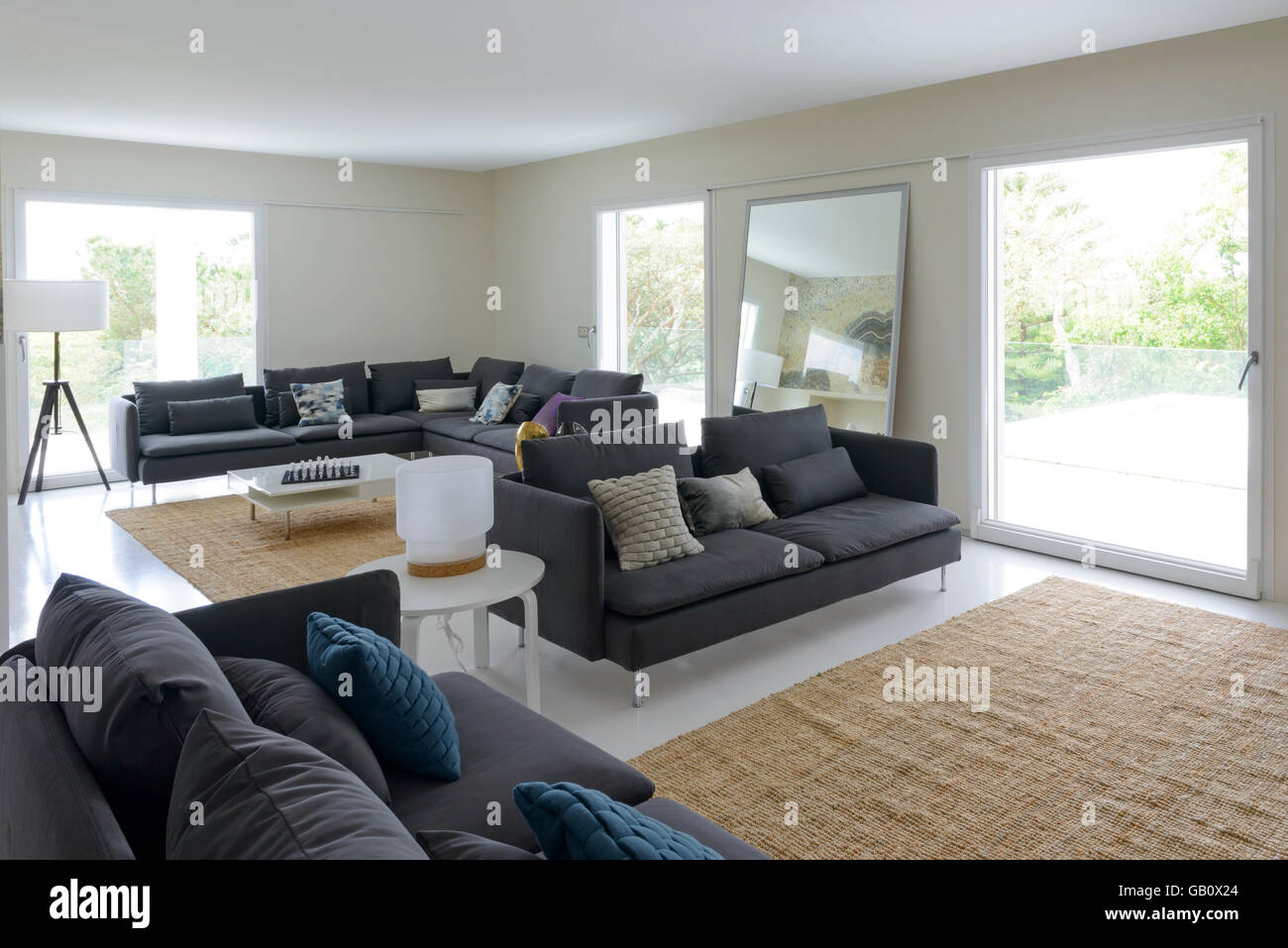 Moderna sala de estar con sofás grandes y luminosas ventanas grandes Foto de stock