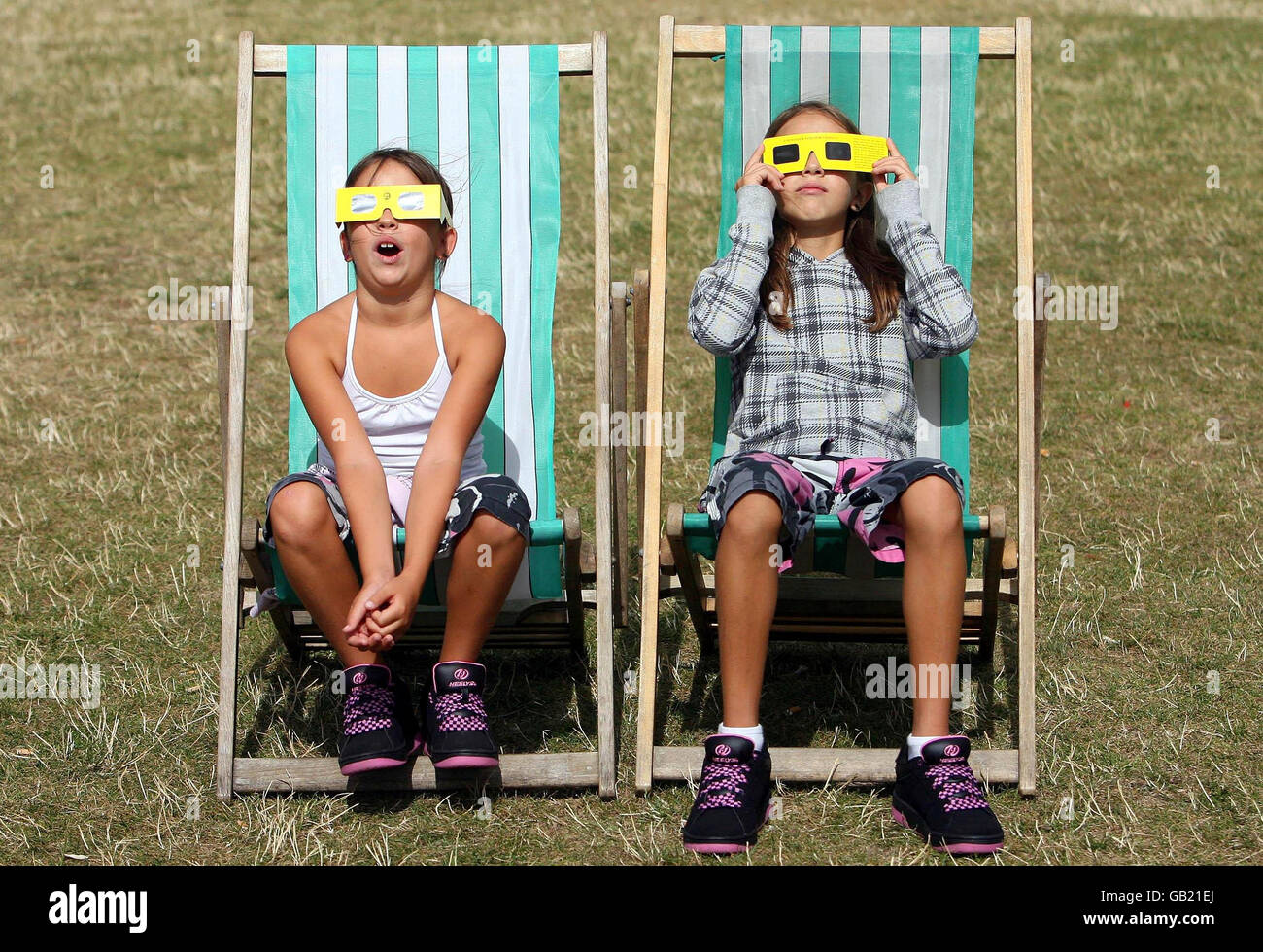 Neza (izquierda), 9, y Ula Pintaric, 11, miran un eclipse solar parcial del sol en Hyde Park, Londres. Foto de stock
