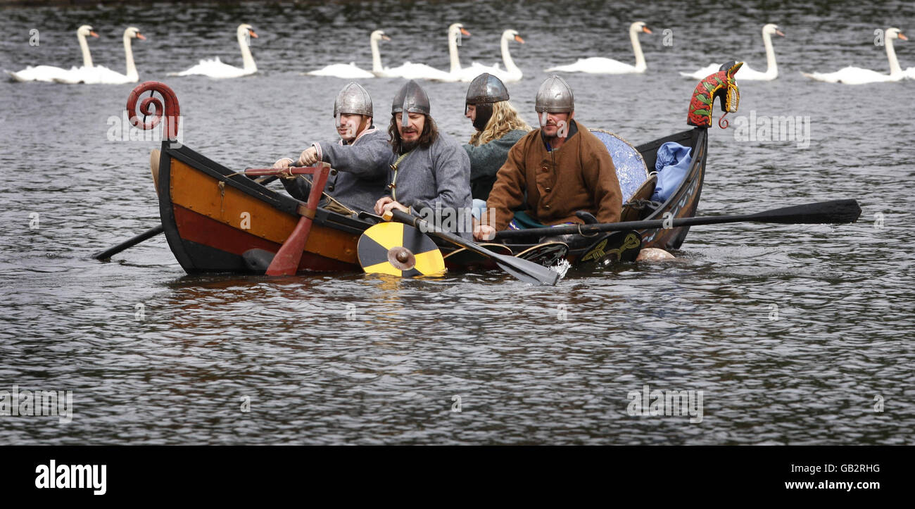 Los entusiastas del Festival Nacional de Historia de la vida en Lanark Loch en Escocia vuelven a crear una escena de la historia mientras los vikingos raiders llegan en un barco largo a las costas de Escocia. Foto de stock