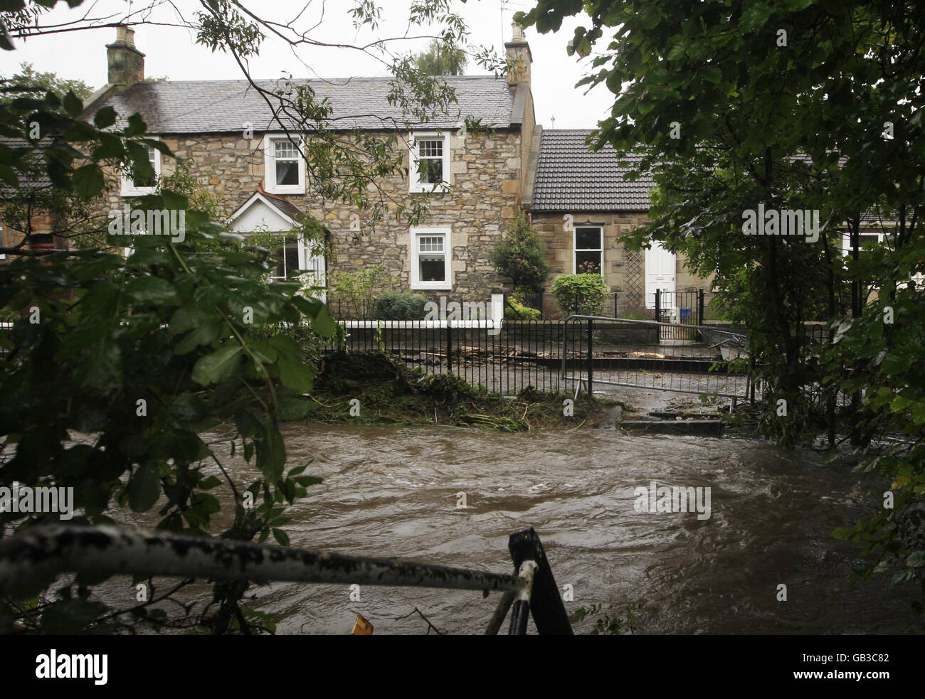 La quemadura de Broxburn, que estalló en sus bancos después de la lluvia intensa de la noche a la mañana, pasa por casas en West Burnside Street en Broxburn, mientras que las inundaciones repentinas azotan partes de Escocia. Foto de stock